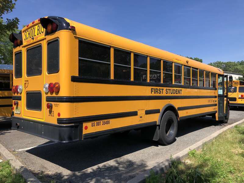 Rear passenger-side view of a First Student school bus at a bus depot in East Orange, Essex County, New Jersey