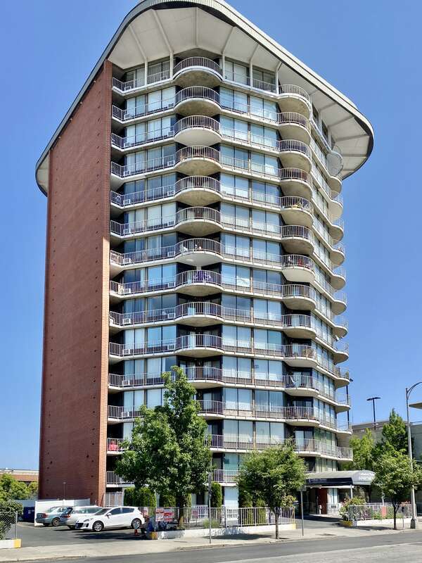 Built in 1971, this Modern International-style building was designed by Warren C. Heylman to serve as the Cathedral Plaza Tower Apartments.  The 15-story building features large glass exterior walls with metal railings, curved balconies at the