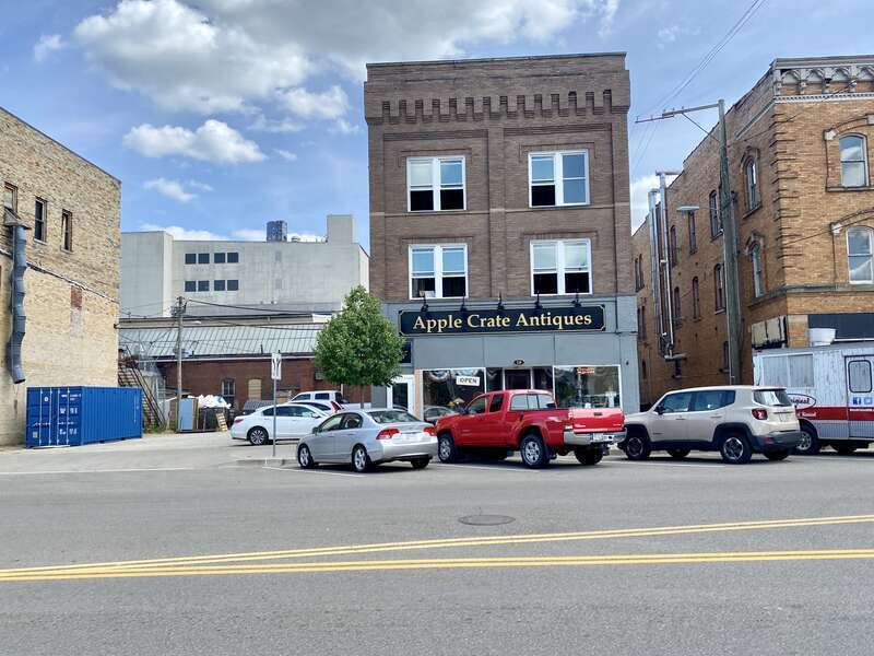 Built around the turn of the 20th Century, this building features a brown brick facade, paired one-over-one windows, stone belt coursing, brick cobbling, a rooftop parapet, a modified first floor retail shopfront, a low-slope shed roof, and an entry