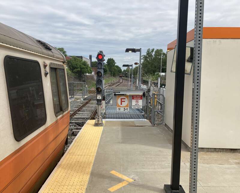 The emergency exit at the north end of Oak Grove station in June 2021. A train is on the normally-unused tail track in the background.