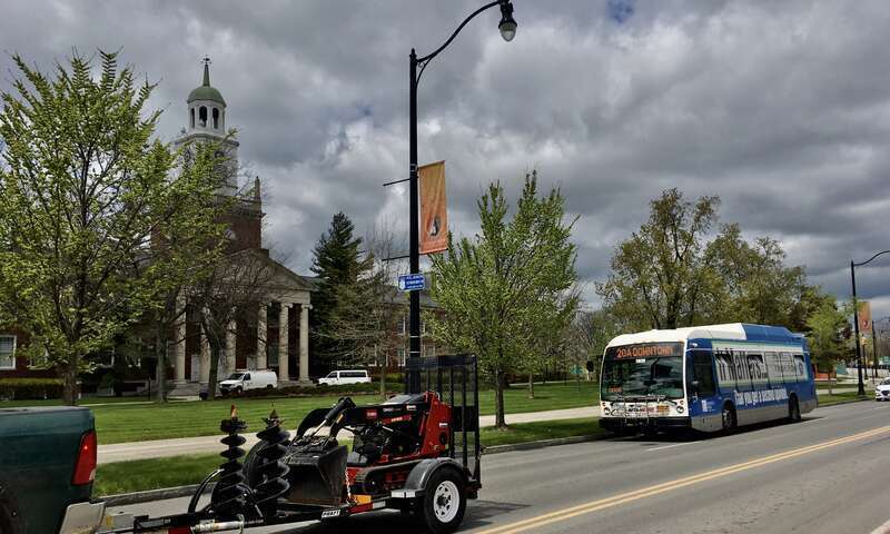 On an April 2021 afternoon, an inbound NFTA Metro Bus #20 passes Buffalo State College's Rockwell Hall on its southward trajectory along Elmwood Avenue, destination Metropolitan Transportation Center.
