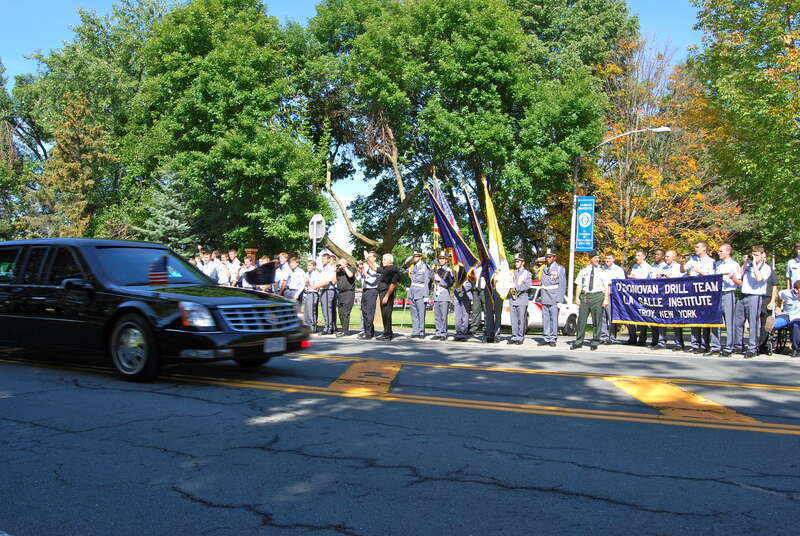 President Barack Obama's motorcade passes by en route to Hudson Valley Community College for a speech regarding higher education and the economy. In the background the students on the Drill Team at La Salle Institute salute the President in full