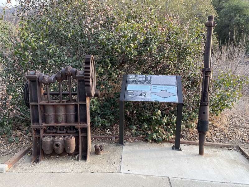 A trailside exhibit showing a small collection oil extraction equipment used in Placerita Canyon during the early 20th century.