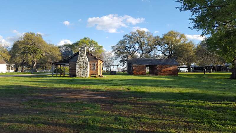 View of three of the historical log cabins on the grounds of the Old Settlers Association, Georgetown, Texas. The cabins of squared logs and hand-hewn limestone were built in the early 1850s near the village of Gabriel Mills, Texas.  They stood on