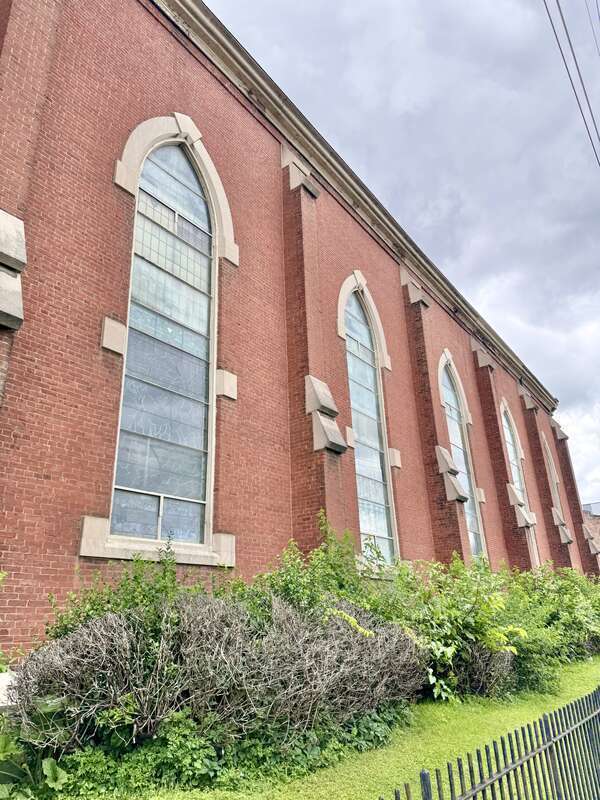 Built in 1866-1867, this Gothic Revival-style building was constructed for St. John’s German Evangelical Church, which later became the St. John United Church of Christ.  The building features a red brick exterior, stone trim, a gable roof, brick