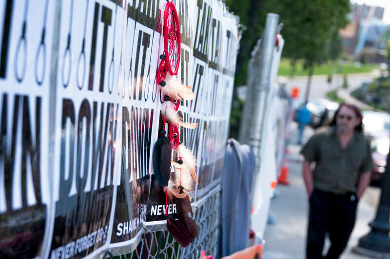 Take It Down signs and dream catcher along the perimeter fence of the Minneapolis Sculpture Garden in response to Sam Durant's &quot;Scaffold&quot; sculpture.
Photograph by Lorie Shaull.
&quot;Scaffold,&quot; a wood &amp;amp; steel sculpture by the artist Sam Durant, was a