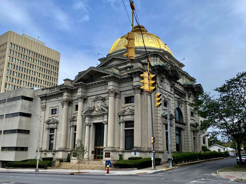 The former Savings Bank of Utica building, 233 Genesee Street at Bank Place, Utica, New York, as seen in August 2021. The finest example of the Beaux-Arts Neoclassical style in the city, this handsome gold-domed edifice was a work of architect Robert