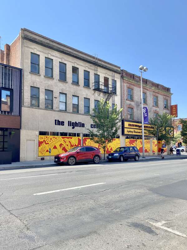 Built in 1906, this Classical Revival-style building features a buff brick facade with decorative patterned brickwork, a modified first floor facade, a cornice with dentils, a metal fire escape mounted to the front facade, and one-over-one