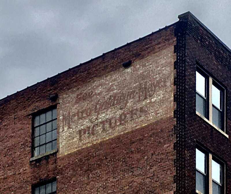 As seen in May 2020: a ghost sign on the rear of the Byers Building in the Theater District of downtown Buffalo, New York, facing West Tupper Street, urges readers to "See Metro-Goldwyn-Mayer Pictures".