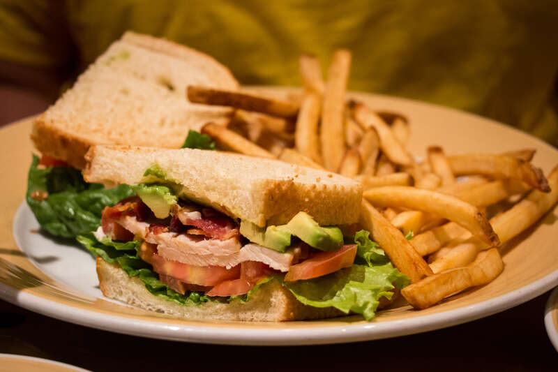 Rae's entree at Storyteller's Cafe: Slow-Roasted Turkey Clubhouse - On Toasted Country Bread with Bacon and Fresh Slices of California Avocado served with French Fries.