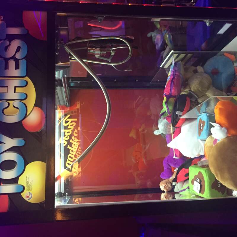 A toy chest brand claw machine filled with toys.
