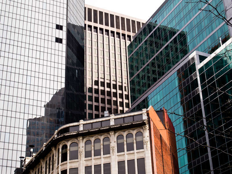 A more meticulously detailed victorian commerical building butts up against 80s glass-and-steel skyscrapers.