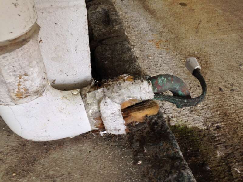 Self-regulating heat tracing tape with the gray end seal next to a copper drain pipe with insulator wrapped around them.