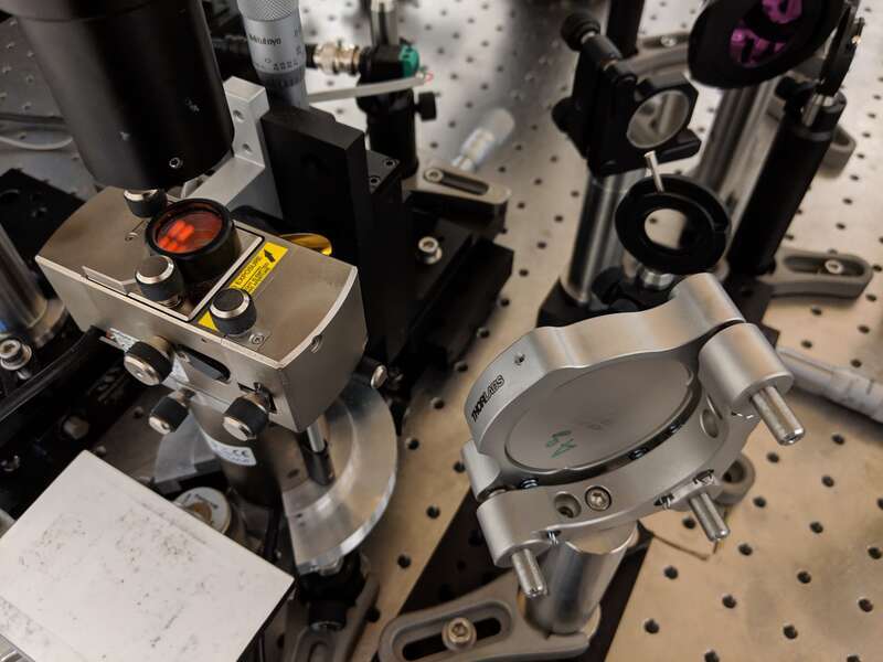 The photo shows an atomic force microscope (AFM) with external optics that guide infrared laser into AFM tip