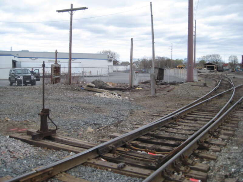 Picture inside the Lawrence yard's left (southeast) side looking at next old manual switch and mechanism a few more yards off the sidewalk from File:2014-0428-IMG 5171-Lawrence,MA Yd, Older switchstand, bent up vandalized target.JPG (short older