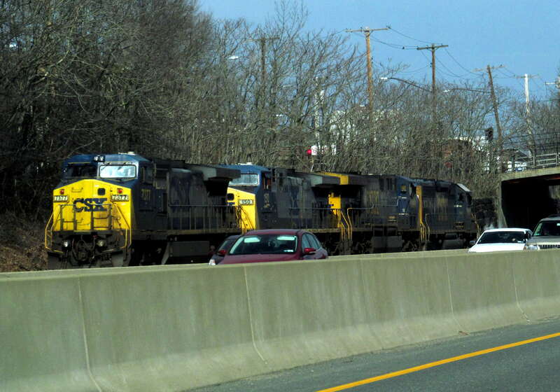 A four-engine train of CSX engines run towards Beacon Park on the MBTA's Framingham Worcester Line along the Mass Pike