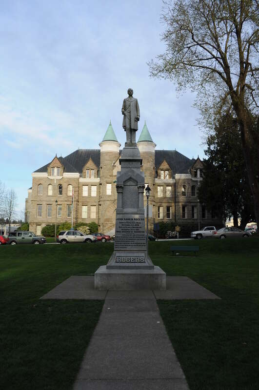 Statue of Washington governor John Rankin Rogers, Sylvester Park, Olympia, Washington; statue dedicated 1905. Behind it is a building that served originally as the Thurston County Courthouse, then as the Washington State Capitol, now the offices of