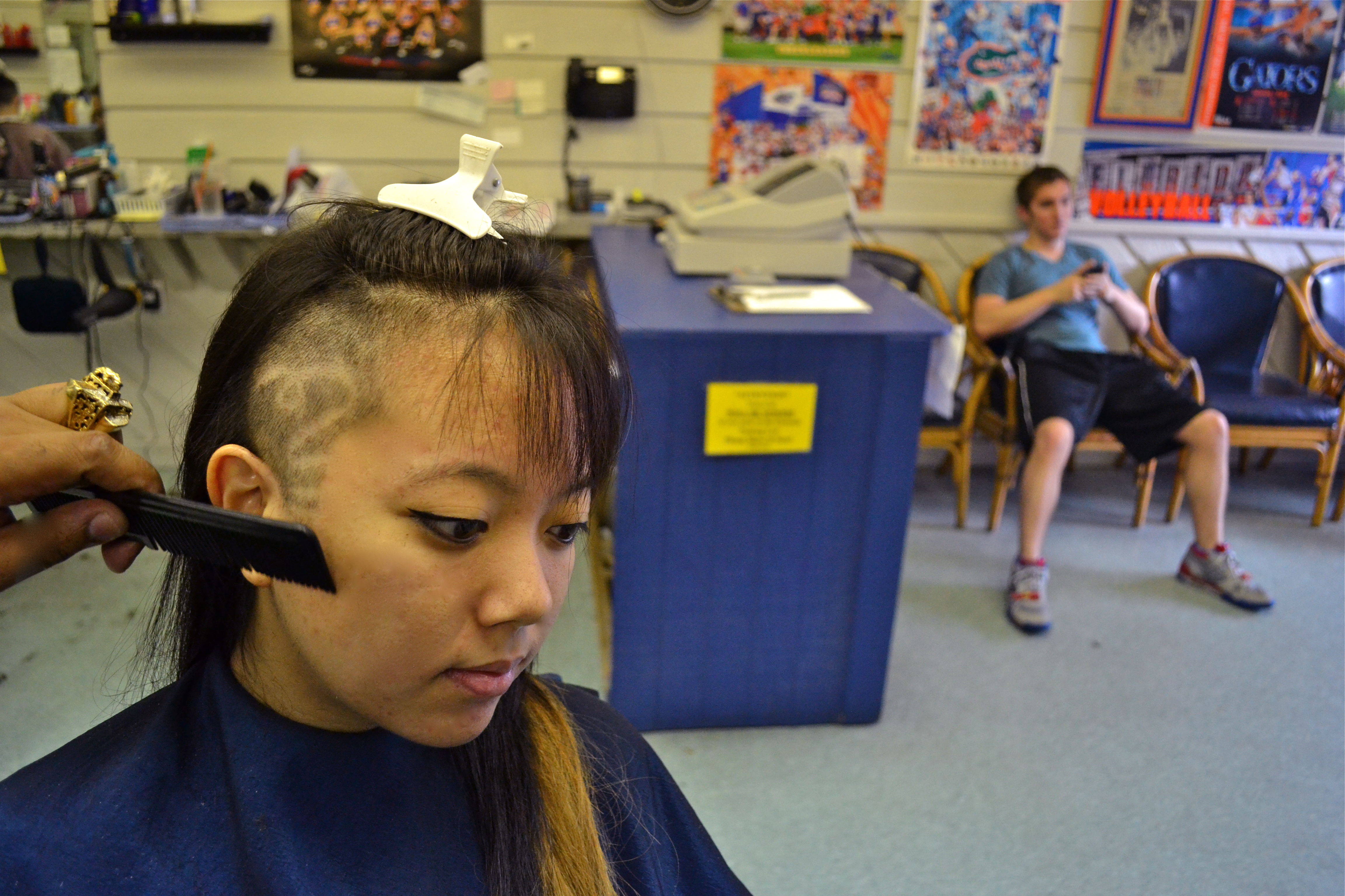April D patiently waits for the debut of her new look.


I was actually just finishing getting my haircut when she walked in flipped her hair over to one side to reveal her attempt at a trendy hairstyle. She asked the barber to attempt to spruce up