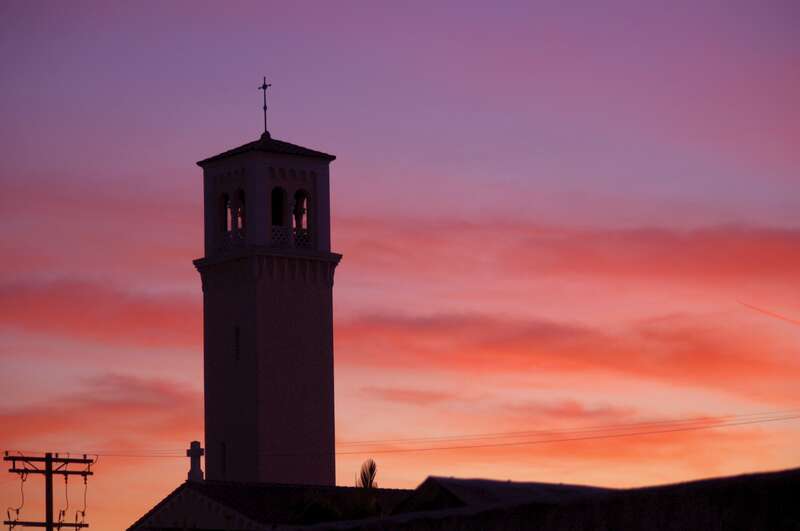 The bell tower of St. Peter and Pauls church is silhouetted by the vibrant hues of a late Fall sunset in the background!