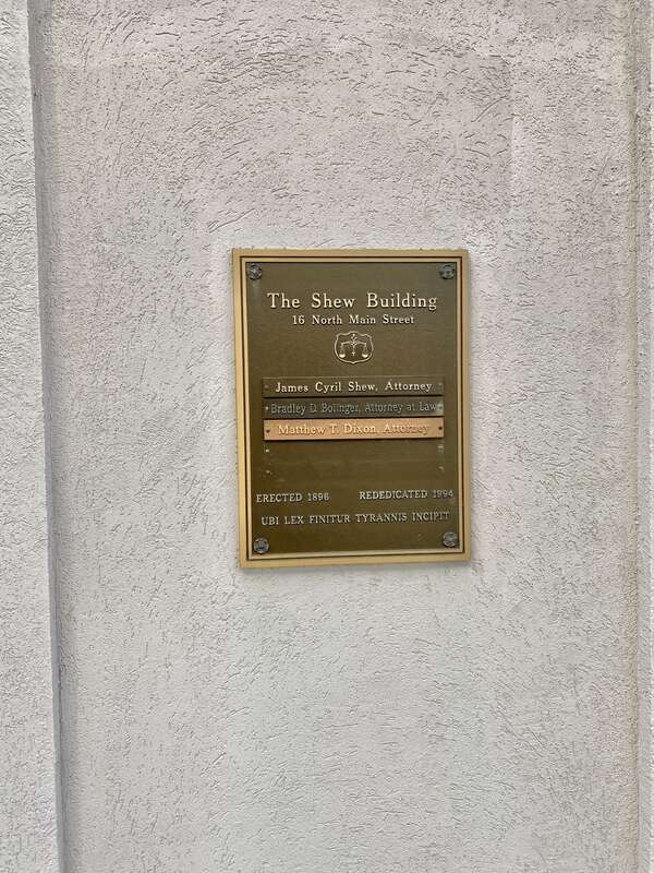 Built in 1896, this Queen Anne-style building is known as the Shew Building, after its present tenant, the Shew Law Office.  The building features a painted brick exterior, an architrave with fleur-de-lis, a cornice with dentils, one-over-one