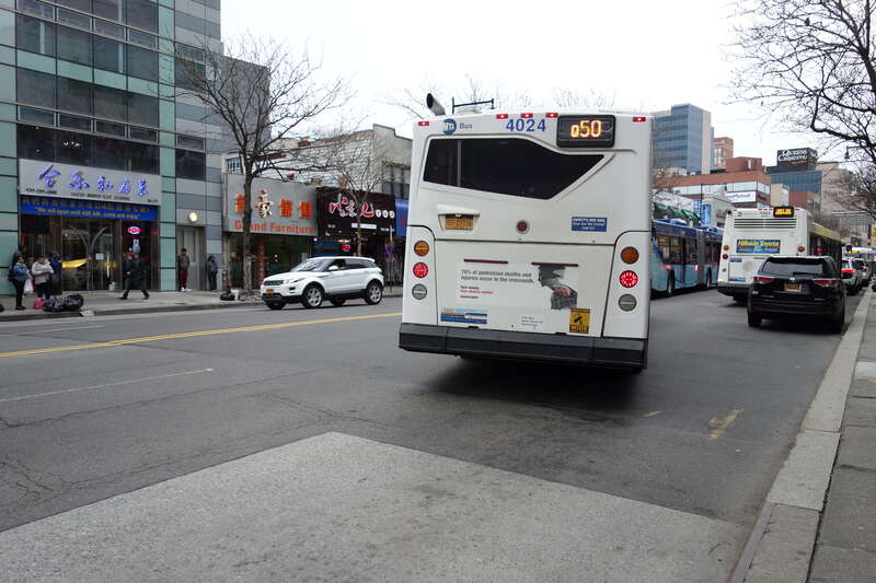A Flushing–Main Street-bound Q50 Limited bus leaving a stop at Main Street and Northern Boulevard in Downtown Flushing, Queens.