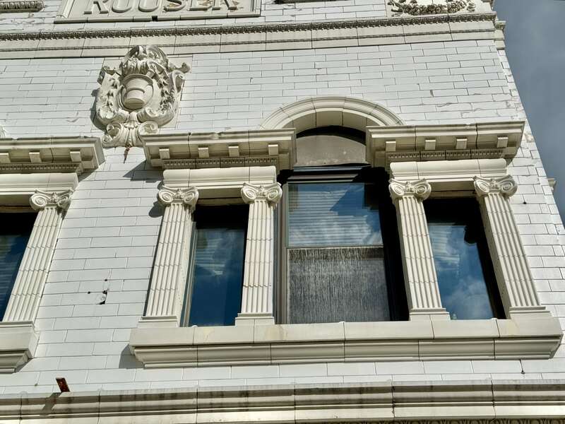 Built in 1855 and renovated to its present First Renaissance Revival-style appearance around the turn of the 20th Century when it was home to the drug store of Christian Rouser, this building is clad in painted brick with a green marble and white