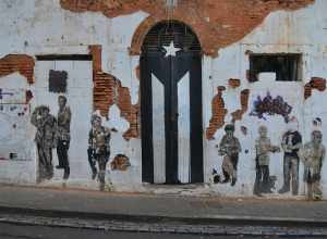 This door used to be painted like a full color Puerto Rican flag.  However, it is now painted as a black and white version of the flag.  The front of the building also has cut-out pictures of people on it.