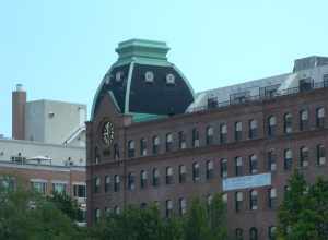 Looking east, full zoom, at Sohmer factory, now apartments, from Socrates Park on a partly cloudy midday.