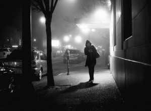 
500px provided description: A woman walking down the street on a foggy night in the city. [#trees ,#city ,#street ,#night ,#lights ,#shadow ,#silhouette ,#woman ,#walking ,#refelction ,#streetlights ,#Fog ,#Coat]