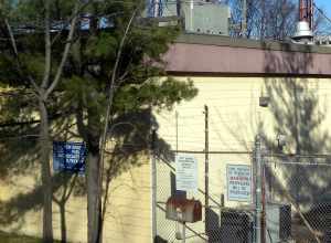 Looking east at signs on the fence of File:WNJN-TV Montclair dishes jeh.jpg on a sunny afternoon.