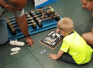 A little boy and his mom work with NRC Region III Project Engineer Nick Shah to identify parts of a nuclear reactor and discuss safety-related systems at D.C. Cook’s annual assessment meeting. Agency inspectors brought interactive items to use as