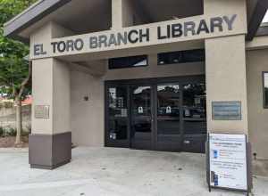 The front entrance of the El Toro Branch Library, a public library with the Orange County Public Library system in Lake Forest, Orange County, California. Legible information includes the name of the library, information about receiving a free phone