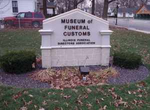 Outside sign at the Museum of Funeral Customs, Springfield, Illinois.  Fallen oak leaves collect on the ground.