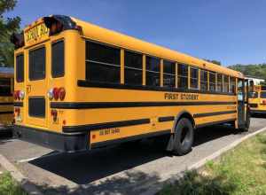 Rear passenger-side view of a First Student school bus at a bus depot in East Orange, Essex County, New Jersey