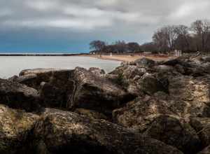 Large limestone blocks form a breakwater for Greenwood Street Beach in Evanston, Illinois.   Early morning, about 10 minutes past  sunrise, looking south.