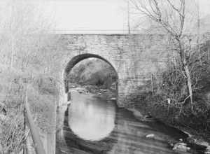 Western (downstream) side of the Bridge in City of Wilkes-Barre, which carries River Street over Mill Creek in Wilkes-Barre, Pennsylvania, United States.  Built in 1885, this single-span stone arch bridge is listed on the National Register of