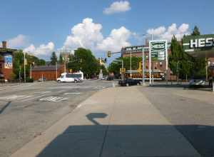 Looking souteast along Merrimack Street near the intersection with Dutton Street.  At left is a canal building from 1848; behind that, Saint Anne's Episcopal Church is visible.  At right is a trolley used to transport visitors throughout the Lowell